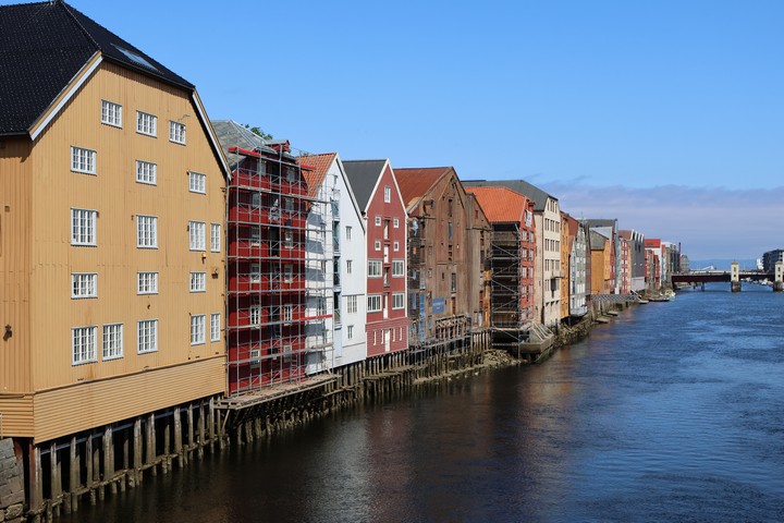 In Trondheim stehen inmitten des Flusses Nidelva auf Stelzen viele bunte alte Holzhäuser und Speicher
