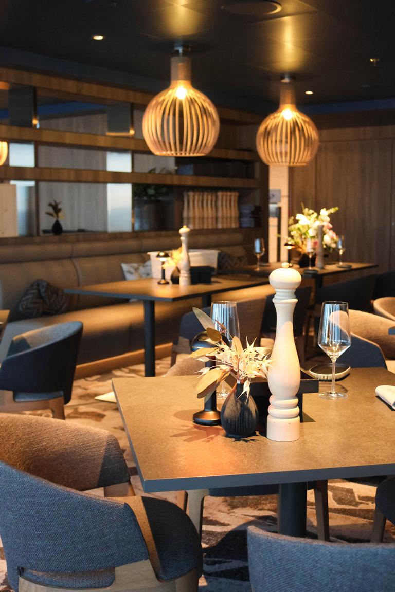Warme Holztöne, dezente Beleuchtung und nordisches Design verleihen dem Restaurant Høfde auf Deck 16 der „Mein Schiff Relax“ eine elegante Atmosphäre
