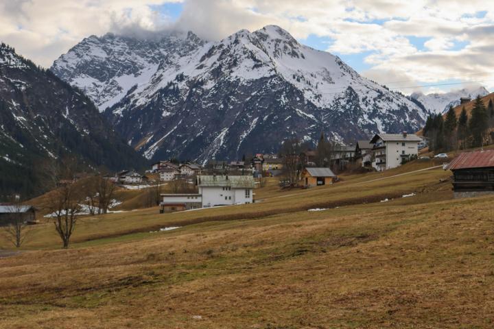 Die Pfarrkirche St. Anna von Hirschegg befindet sich im Zentrum des Dorfes. Dahinter erheben sich die markanten Gipfel Zwölferkopf (2224 m) und Elferkopf (2387 m), die sich an der Grenze zwischen Österreich und Deutschland befinden