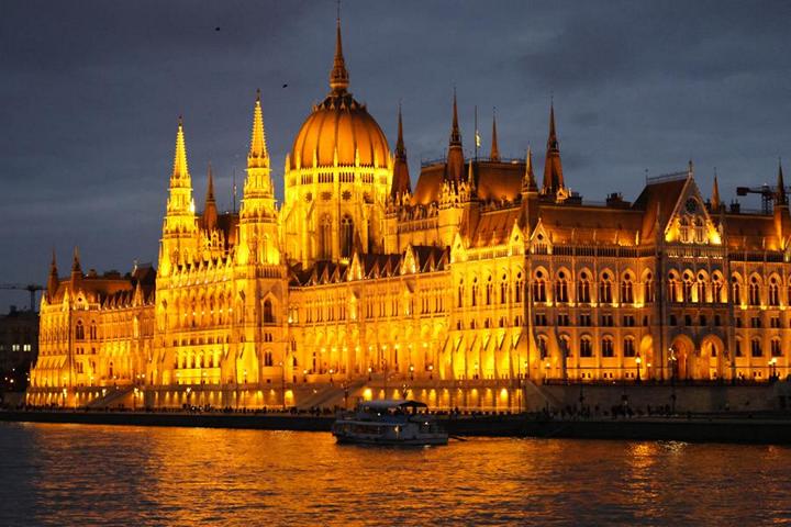 Das prächtige ungarische Parlamentsgebäude erhebt sich majestätisch und prachtvoll angeleuchtet in der Abenddämmerung am Ostufer der Donau im Stadtteil Pest