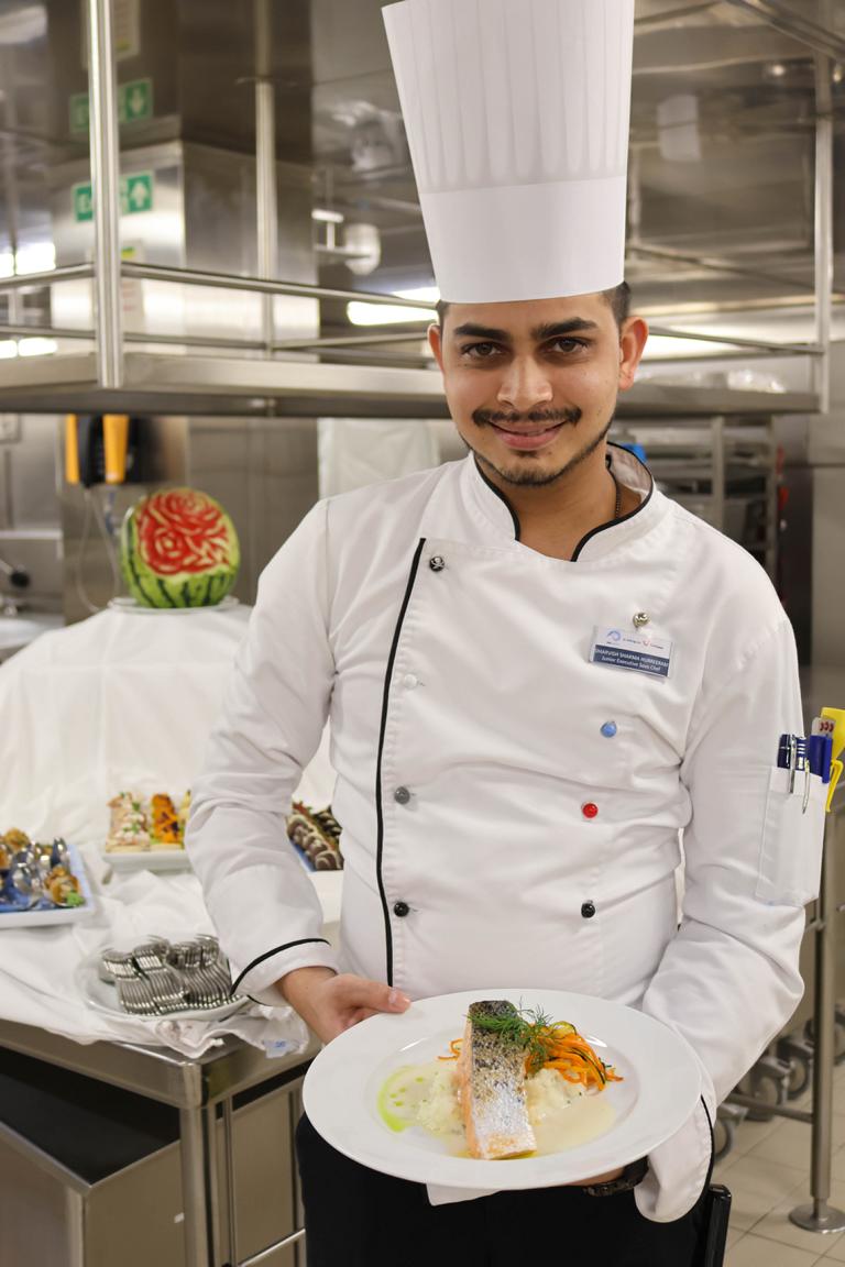 Junior Executive Sous Chef Dharvish Sharma Hurreeram präsentiert in der Hauptgally ein frisch zubereitetes Lachsgericht, das anschließend im Rahmen der täglichen Qualitätskontrolle bewertet wird