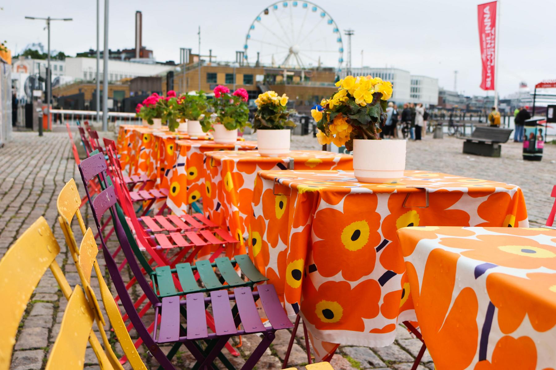 Besucherinnen und Besucher passieren den belebten Marktplatz (Kauppatori) am Südhafen von Helsinki. Nur wenige Schritte entfernt, auf der Prachtstraße Esplanade, verbindet das gastronomische Sommerkonzept von Marimekko finnische Kaffeekultur mit den weltberühmten, farbenfrohen Mustern des heimischen Designhauses