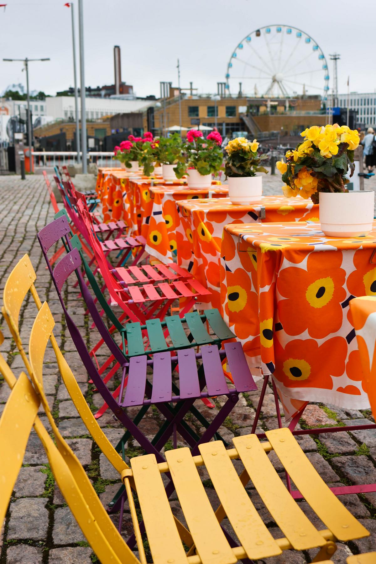 Besucherinnen und Besucher passieren den belebten Marktplatz (Kauppatori) am Südhafen von Helsinki. Nur wenige Schritte entfernt, auf der Prachtstraße Esplanade, verbindet das gastronomische Sommerkonzept von Marimekko finnische Kaffeekultur mit den weltberühmten, farbenfrohen Mustern des heimischen Designhauses